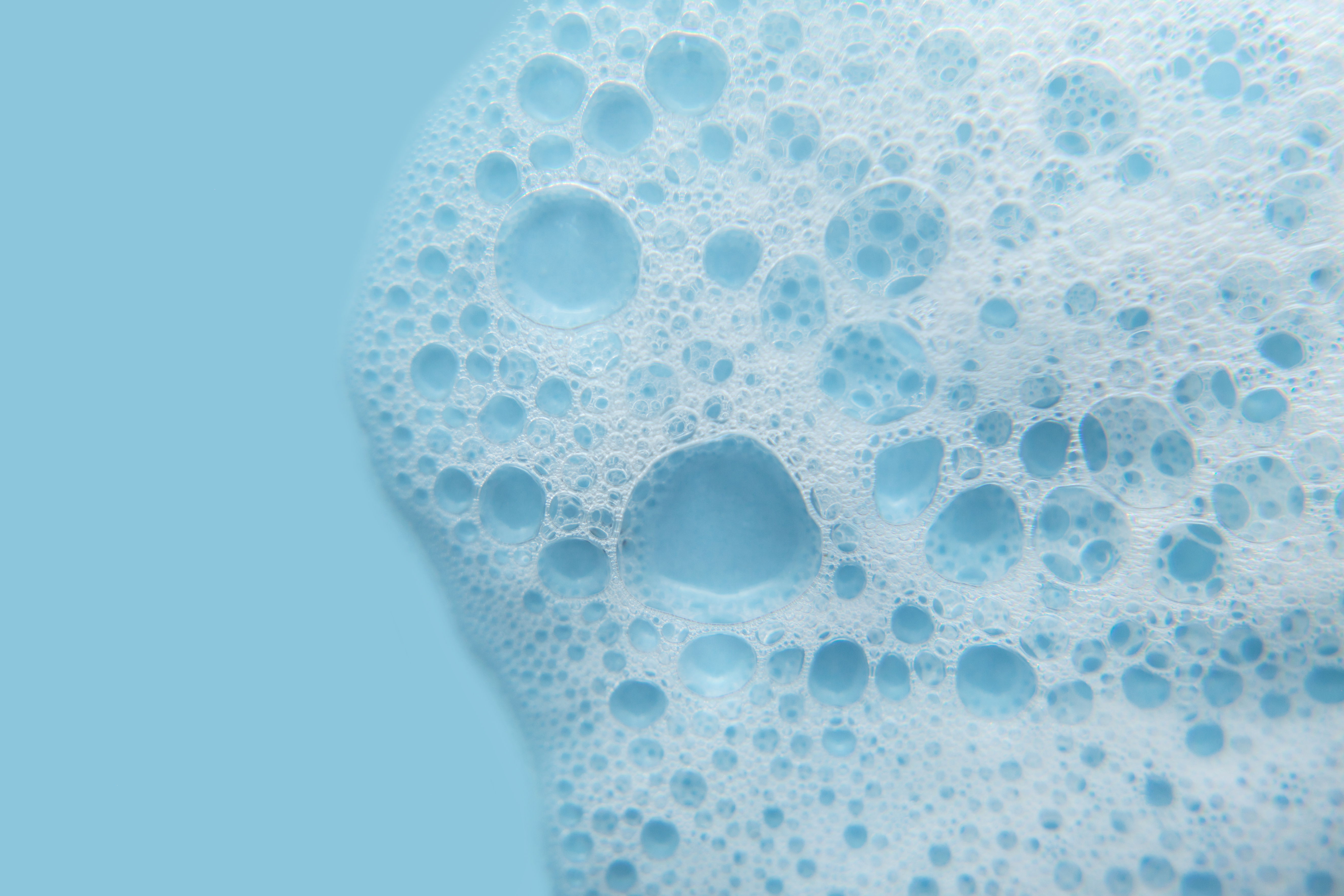 close-up of white, frothy sudsy bubbles on a vibrant background.